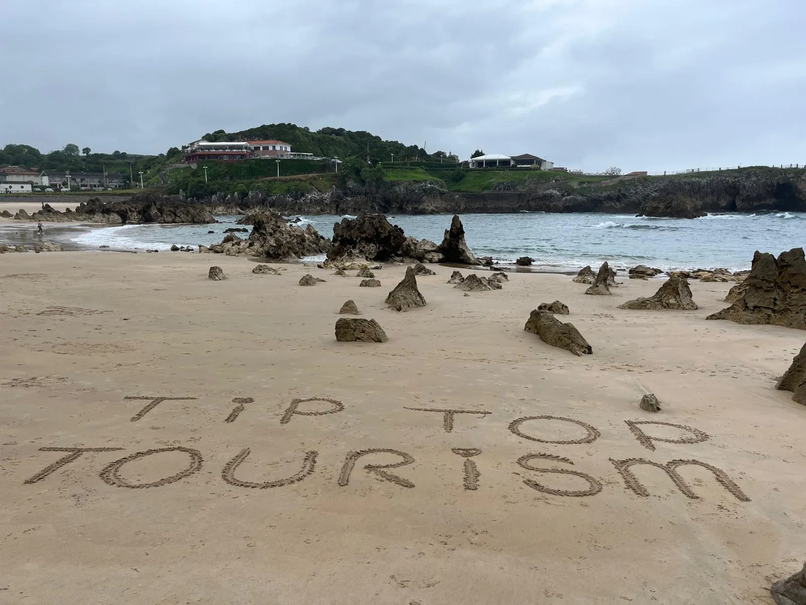 Tip Top Tourism escrito en la arena de la playa
